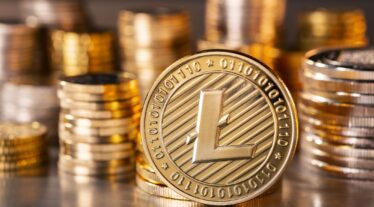 standing golden Litecoin coin with a stack of coins in the background